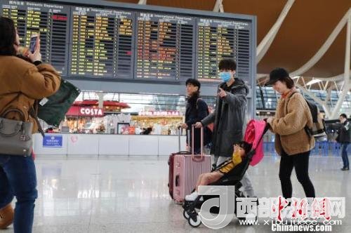 旅客帶著孩子前往辦票柜臺辦理登機手續(xù)?！∫罅⑶?攝