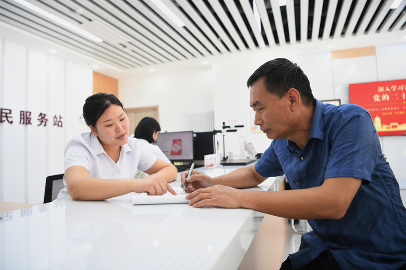 2023年5月23日，河北雄安新區(qū)容東片區(qū)南文營(yíng)社區(qū)居民（右）在社區(qū)便民服務(wù)站辦理業(yè)務(wù)。